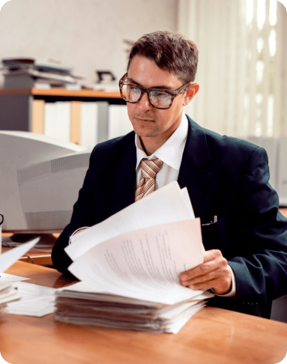 Man in glasses reviewing documents at desk.