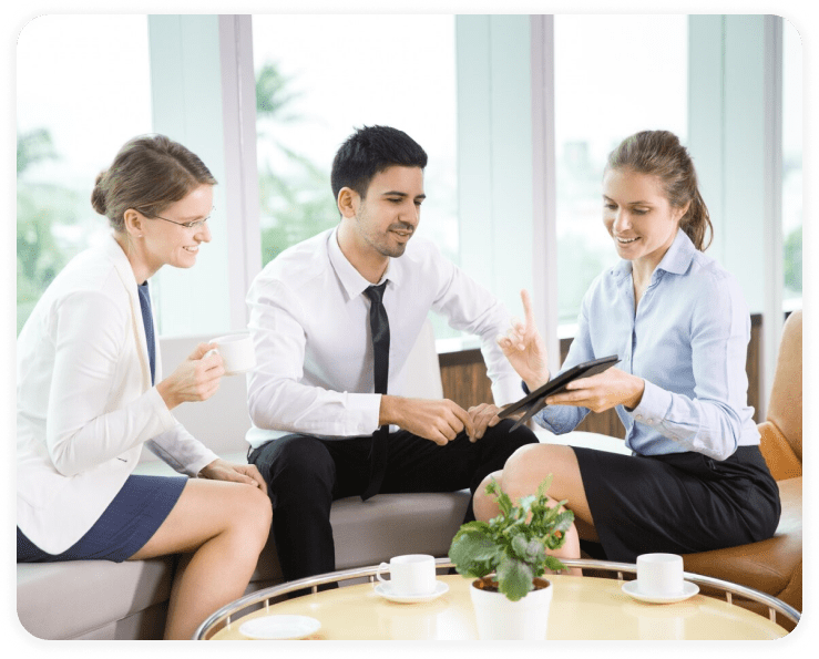 Three people discuss business over coffee.