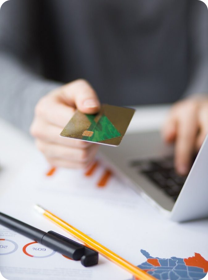 Person holding credit card over laptop.