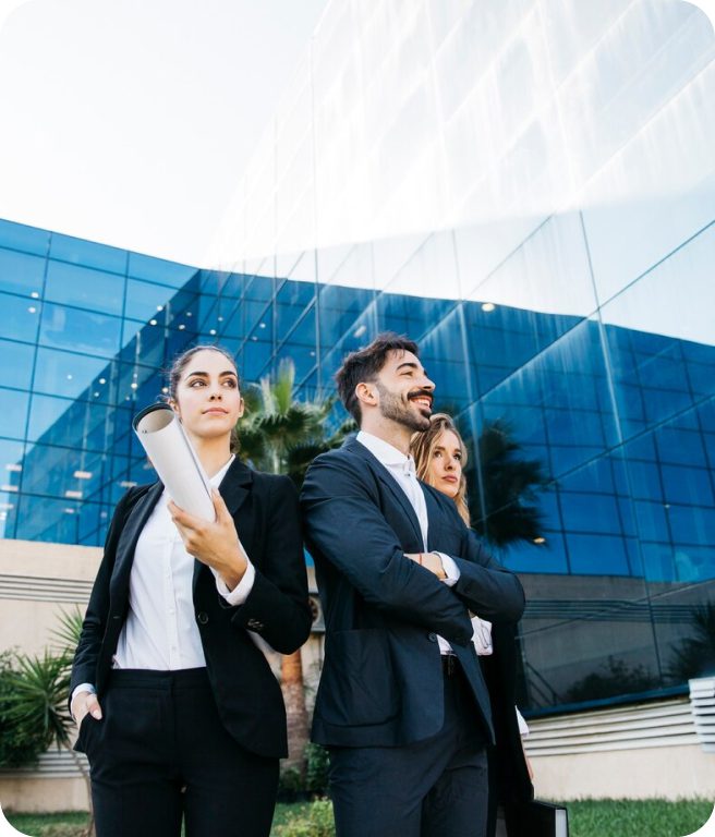 Three businesspeople standing in front of building.