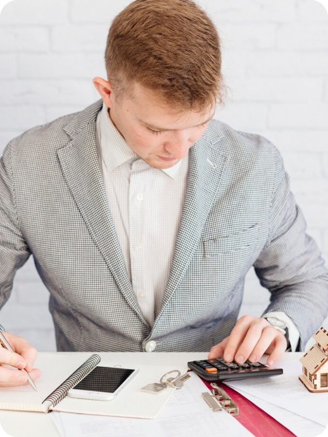 Man in suit using calculator and pen.