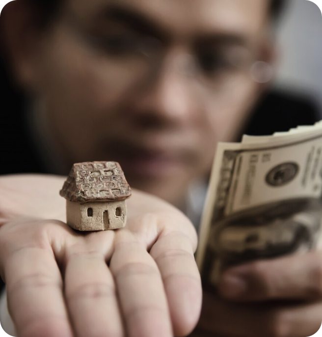 A man holding a model house and money.