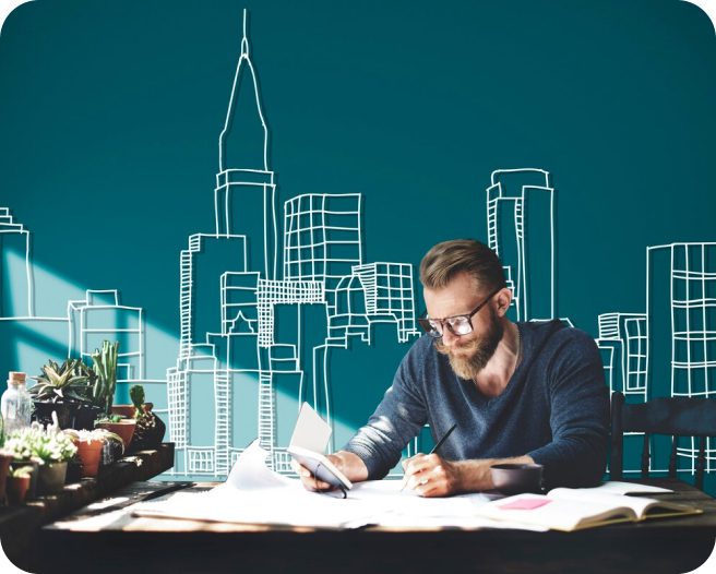 Man working at a desk with city skyline drawing.