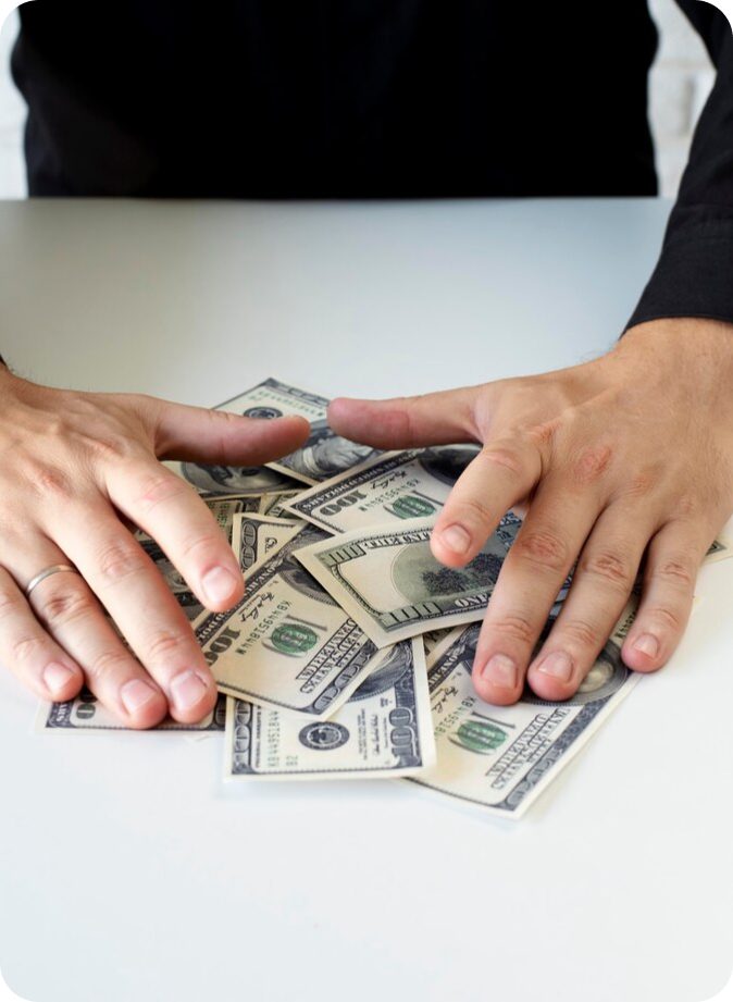 Hands on a pile of US dollar bills.