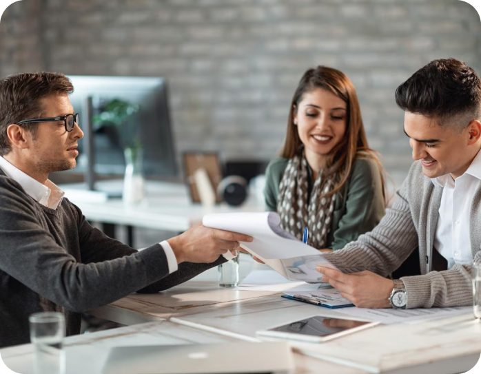 Three people reviewing documents at a meeting.